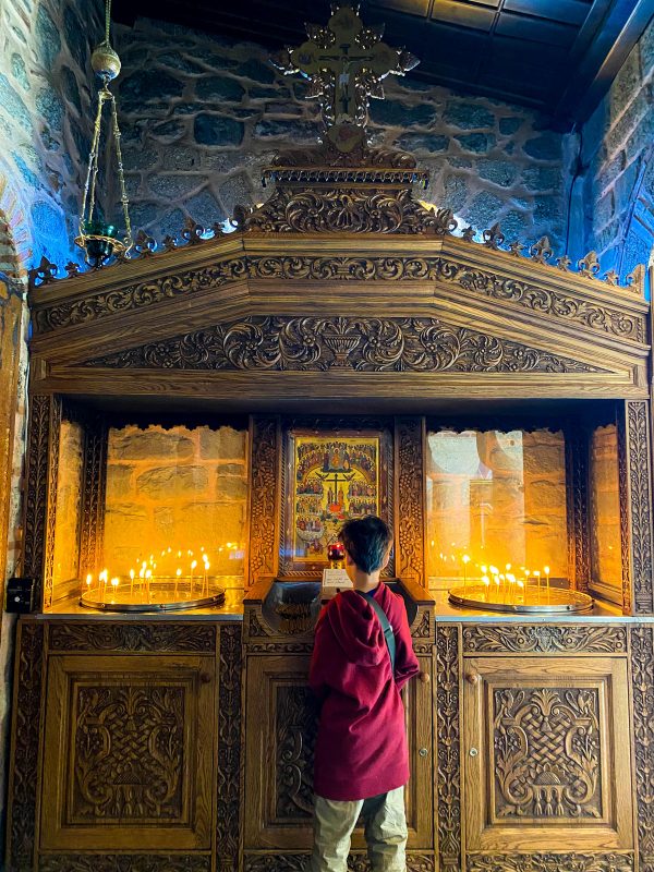 A boy lights a candle at a monastery in Meteora Greece