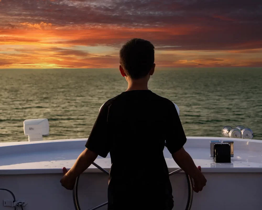 A boy steers a cruise ship through the ocean in the Galapagos Islands