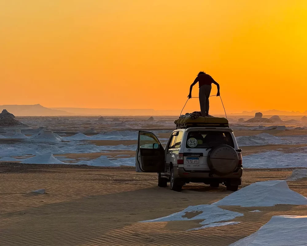 Bedouin setting up an overlanding camp at sunset in Egypts White Desert