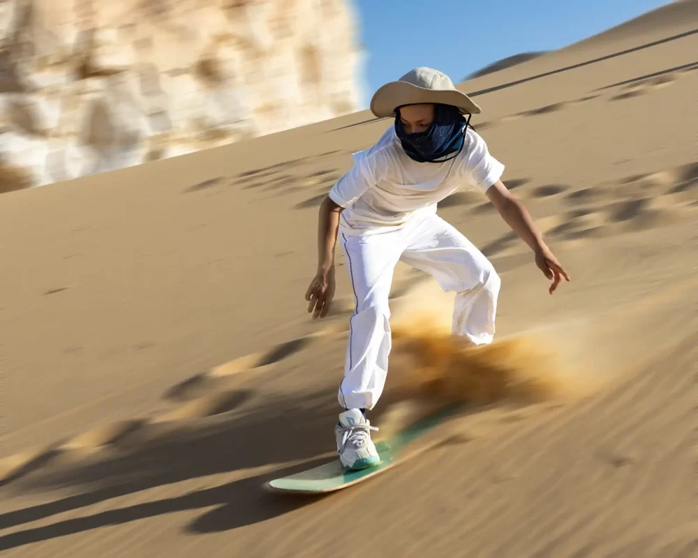Boy sandboarding down a dune in Egypts Western Desert