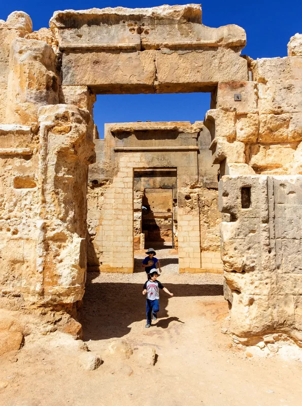 Two boys race through the Temple of Alexander in Siwa Egypt