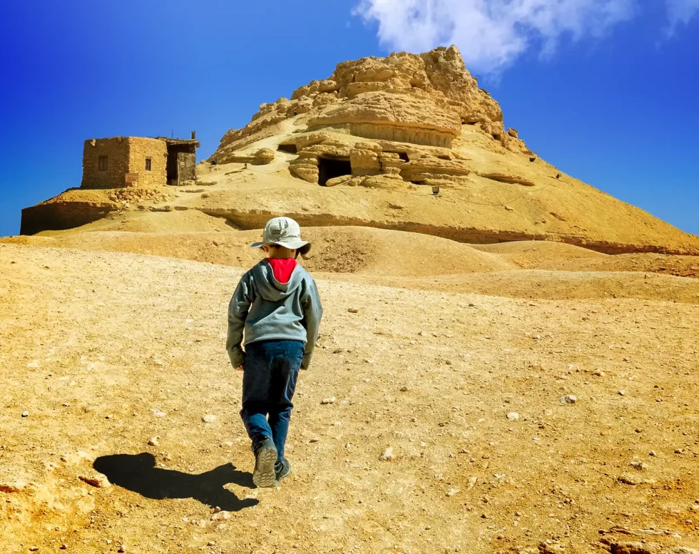 Young boy hiking toward the mountain of the Dead in Siwa Egypt